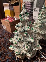 Front and side view of the ceramic Christmas tree showing the green and blue speckled paint with green tipped branches and attached lights. The damaged tip is visible.