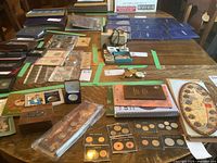 Wide view of table showing multiple coin albums, holders, commemorative coins, books and wooden box with carriage emblem