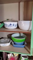 Top shelf shows the blue cornflower Corning Ware baking dish with glass lid and white Glassbake mixing bowl next to it.