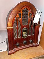 Frontal view of the radio showing the wood cathedral-style cabinet and three controls.