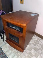 Full view of floor infrared heater in wooden cabinet with front control panels and vent.