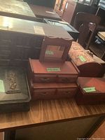 Photo of multiple wooden jewelry boxes displayed on a wooden table showing different sizes and styles clustered together.