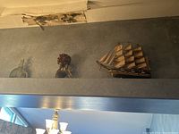 Model ship, topiary, and oil lamp displayed on a high shelf.