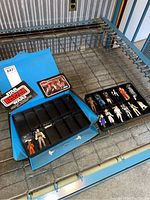 Blue vinyl carrying case open with removable black plastic tray, showing assorted vintage Star Wars action figures and two printed character booklets