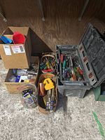 Photo showing the plastic toolbox with tools inside and nearby cardboard boxes containing hardware and funnels.