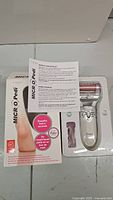 Boxed Emjoi Micro-Pedi foot care device, instruction manual, and packaging showing product features and benefits.