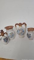 Front view of four small decorative ceramic pitchers with Italian map artwork
