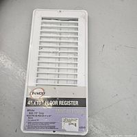 Front view of white metal floor register with horizontal slats and product label showing size 4"x10" and brand Tanco.