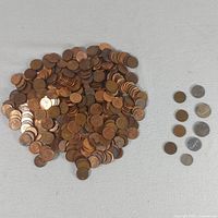 Pile of copper pennies with seven separate silver-coloured coins displayed to the side