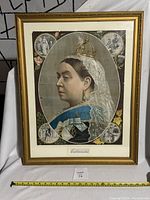 Full view of framed lithograph of Queen Victoria showing overall condition and size with measuring tape.