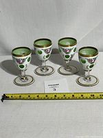 Set of four antique Moser Bohemian Czech glasses arranged in a row with measuring tape below for scale.