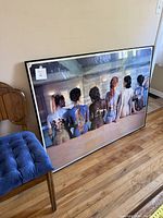 Full front view of the large framed print showing seven women with Pink Floyd back art body paint sitting on a tiled floor.