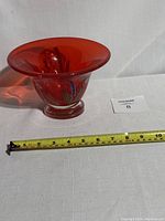 Red art glass pedestal bowl with millefiori pattern, front angle showing size alongside measuring tape.