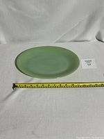 Oval jade green glass platter with measuring tape showing length approx. 14 inches