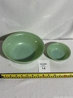 Two Fire-King jadeite glass bowls, one large and one small, placed side by side showing scale.