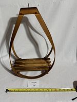 Front view of wooden mid century plant hanger showing the teardrop shape and slatted base with ruler for scale.