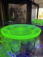 Photo of one Vaseline uranium glass plate under UV light showing bright green fluorescence, starburst pattern visible.