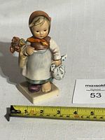 Front view showing the figurine's front details, size relative to measuring tape, and seller's tag.