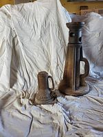 Full view of two barn jacks on a draped white cloth showing size difference and condition.