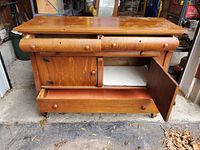 Front view of walnut buffet showing two top drawers and two cupboard doors below with the large shallow bottom drawer open on the bottom.