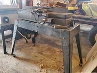 Full view of jointer mounted on metal stand with motor underneath
