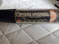 Close-up of umbrella handle showing Canada Umbrella Topper label from Vancouver, B.C.