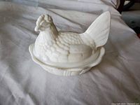 Milk glass hen in nest covered dish photographed closed showing textured hen lid with detailed features such as feathers and tail.