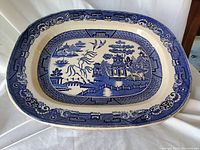 Large blue and white ceramic platter with willow pattern design