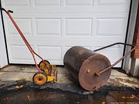 Wide view of the push reel mower and the rusted water-fillable lawn roller.