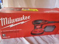 Original red Milwaukee box showing the product image and branding, model number 6034-21 5 inch random orbit palm sander.
