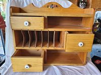 Full front view of the shelf showing four drawers with white knobs, multiple vertical dividers for sorting, and shelf compartments.
