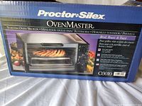 View of the front of the box showing Proctor Silex OvenMaster branding and image of toaster oven with food inside.