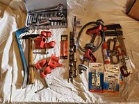 Photo of Craftsman 3/8" socket set with ratchets and multiple sockets; red pipe clamps and C-clamps alongside hammer and pry bar on a white cloth.