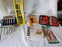 Wide view of unopened tools including screwdriver sets, Forstner bit set, magnetic holder, folding hex key wrench set, and tuning fork