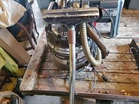 Full view of Filter Queen vacuum with attached hose and floor brush on wooden table