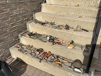 Wide view of assorted vintage kitchen utensils arranged on stairs showing graters, sieves, egg beaters, and handheld tools.