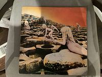 Front view of the album cover showing rock formation with nude children climbing, under an orange sky.