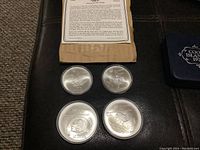 Four coins in protective capsules with original packaging and case