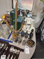 Photo showing African carved human and animal figures, wooden chicken decor, ceramic dishes and metal ashtray with wooden sticks