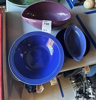 Purple, blue ceramic bowls and clear glass plates displayed on table.