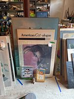 Photo showing entire lot with two large framed cat posters, two cat-themed books, and a small cat figurine arranged on the floor.