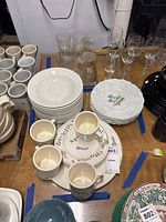 Top view showing stacked white Buffalo China bowls, Royal Cauldon dinner plates with floral designs, and vintage style serving plate with text.