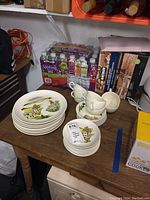 Full set of dinner plates, bread plates, saucers, and cups displayed on wooden table in storage area
