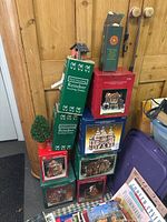 Stacked boxes of Santa's Workshop collectible houses and reindeer stocking holders with Christmas decoration boxes outside packaging.