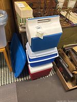 Stacked view of three portable coolers including a blue and white cooler on top, white and blue in the middle, and red and white at the bottom.