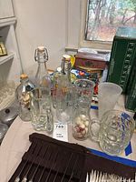 Photo of vintage and retro style bottles with swing-top lids and various glass mugs, along with decorative ship in a bottle