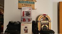Tray showing the lot items stacked including the vintage jukebox radio, boxes for mini cooler and transceiver, camera box, and bags