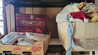 Wide view of the sewing box, box of patterns, and container of fabric placed on shelves.
