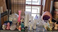 Wide shot showing all assorted glass and ceramic items including skull vase, Mickey Mouse figurine, ceramic jar, and colorful glass vases.
