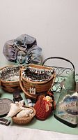 Photo shows Longaberger baskets with fabric liners, smaller baskets, decorative ceramic Maine item, harmonica in black case, metal basket frame, decorative face sculpture with large flower petal headpiece, and assorted small decorative objects.